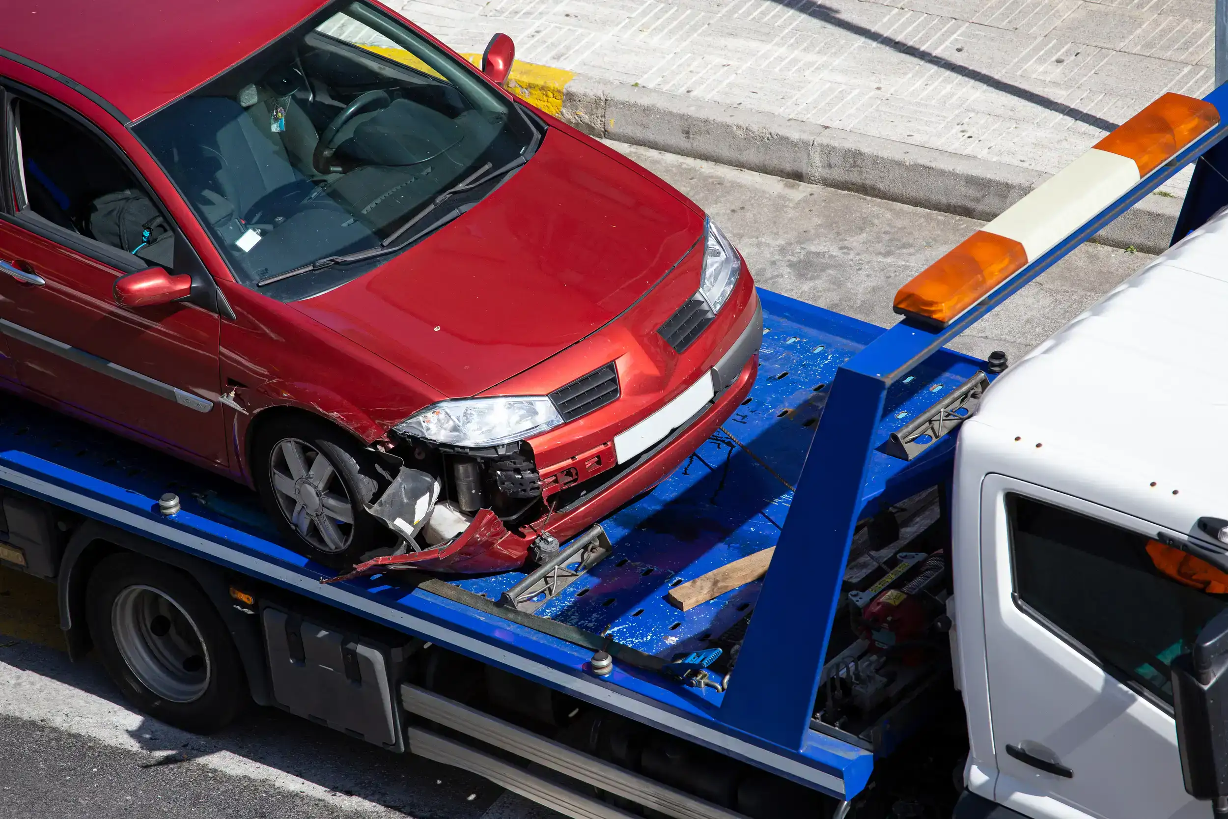 Crashed red car loaded onto a blue tow truck, illustrating Beck's Towing Road and Beach Recovery services in Ocean Shores, WA.